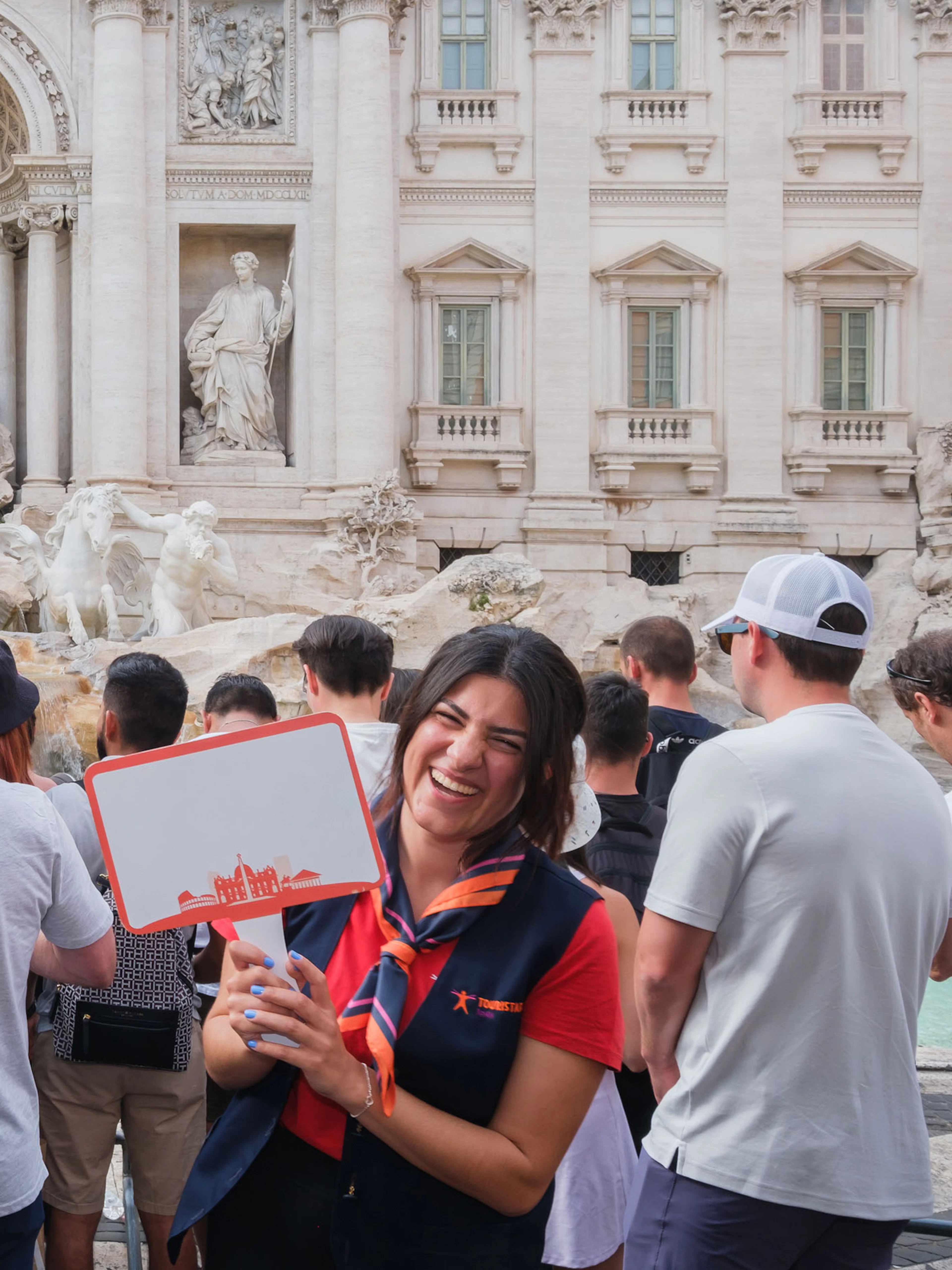 Guide leading a tour at the Trevi Fountain in Rome with a group of tourists.