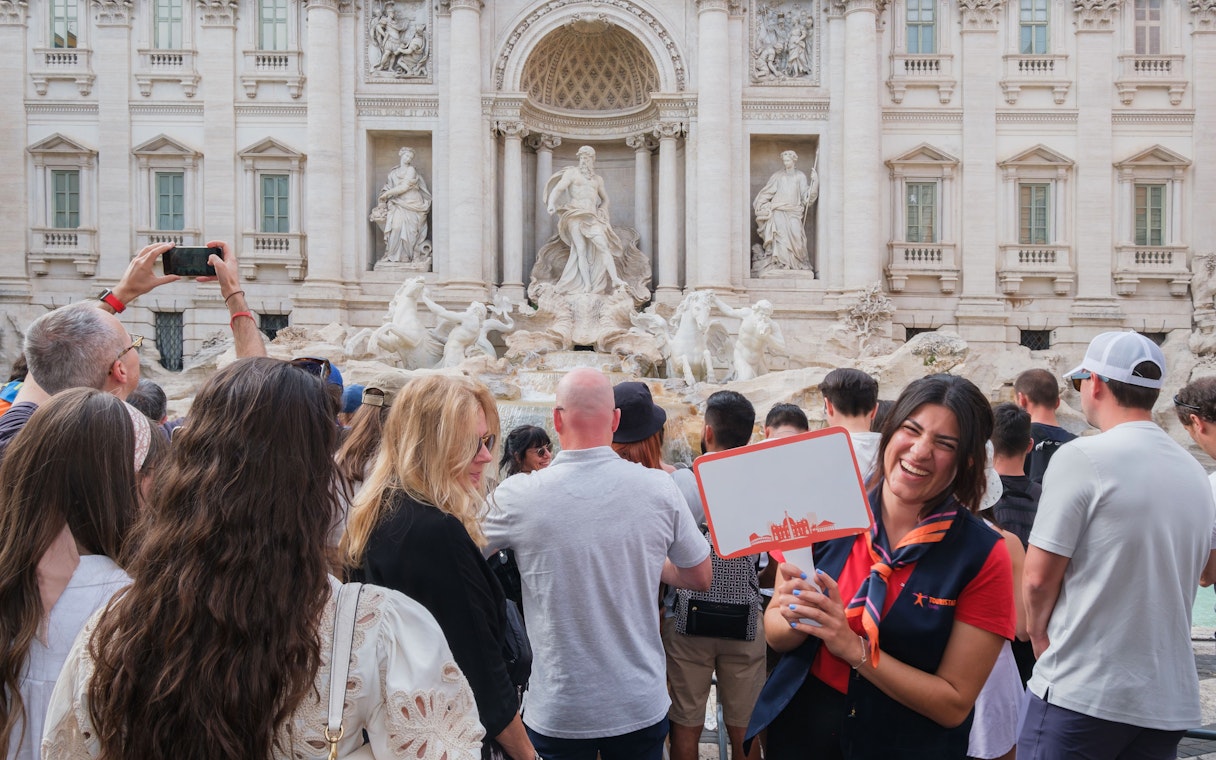 Guide leading a tour at the Trevi Fountain in Rome with a group of tourists.