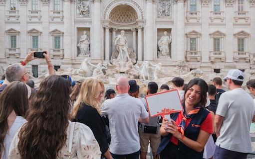 Guide leading a tour at the Trevi Fountain in Rome with a group of tourists.