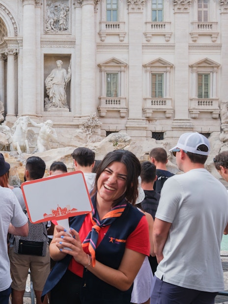 Guide leading a tour at the Trevi Fountain in Rome with a group of tourists.