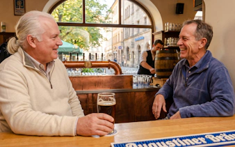 Men enjoying beer at a Munich pub during Oktoberfest keg tapping tour.