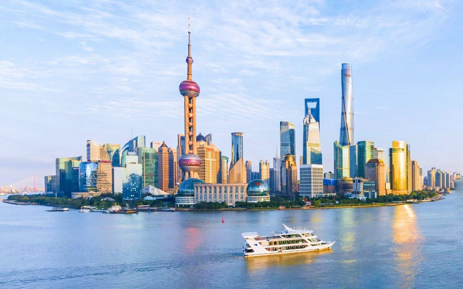Cruise boat on Huangpu River with Shanghai skyline in the background.
