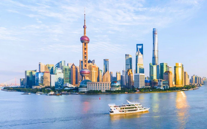 Cruise boat on Huangpu River with Shanghai skyline in the background.