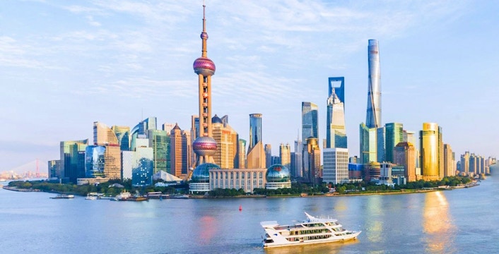 Cruise boat on Huangpu River with Shanghai skyline in the background.