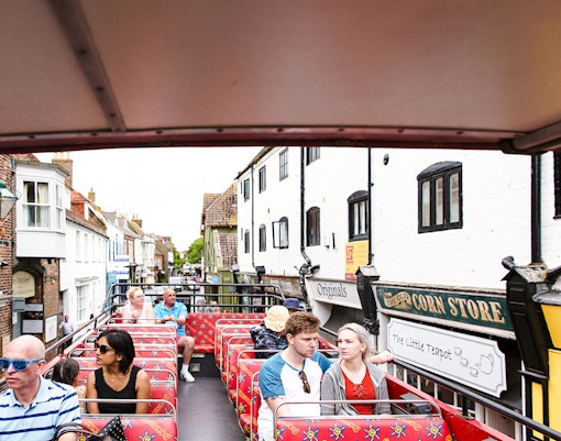 Open-top bus tour passing historic buildings.
