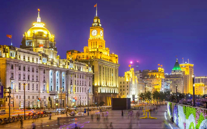Shanghai Bund waterfront at night with illuminated historic buildings.