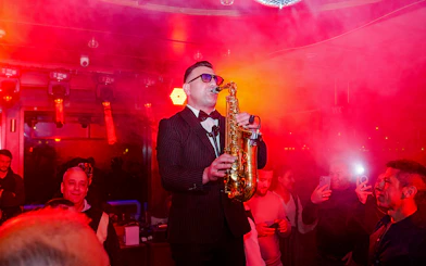 Saxophonist performing on Bosphorus dinner cruise with audience in background.