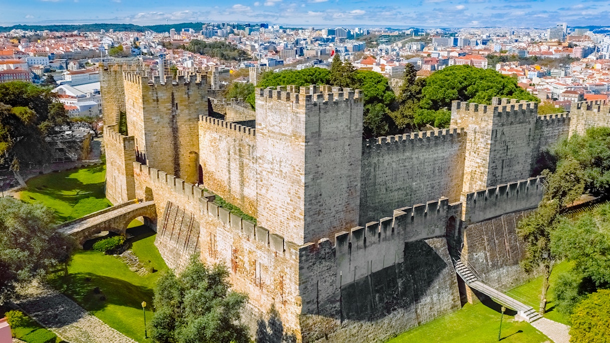 Aerial view of Sao Jorge Castle in Lisbon, Portugal, with cityscape in the background.