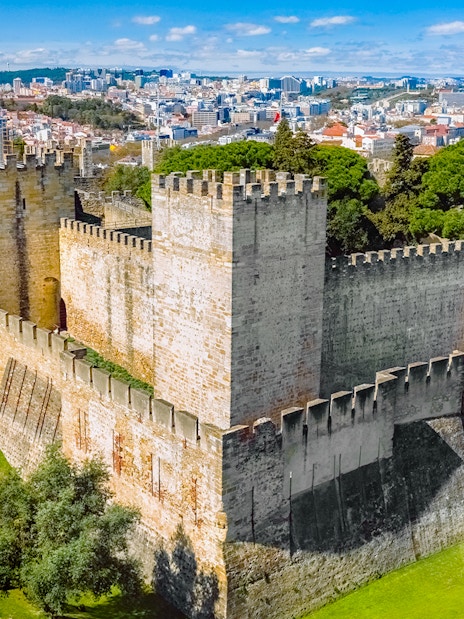 Aerial view of Sao Jorge Castle in Lisbon, Portugal, with cityscape in the background.