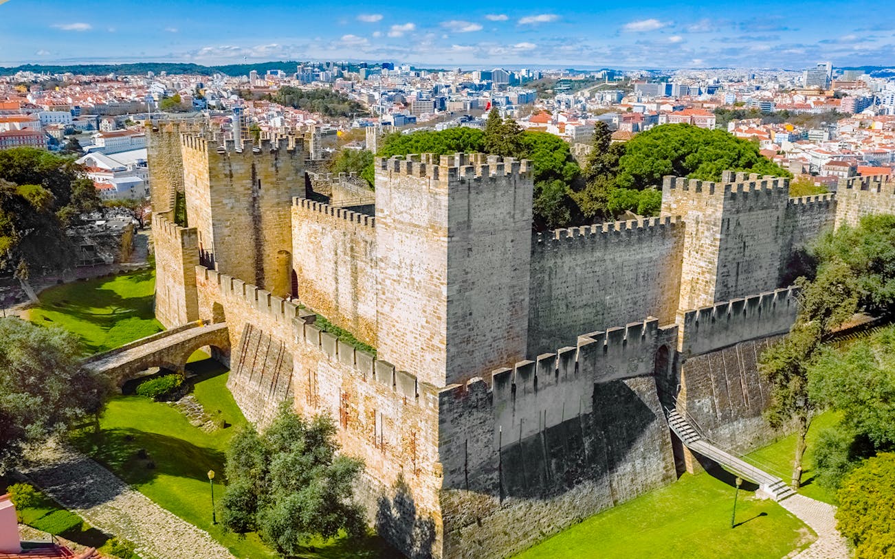 Aerial view of Sao Jorge Castle in Lisbon, Portugal, with cityscape in the background.