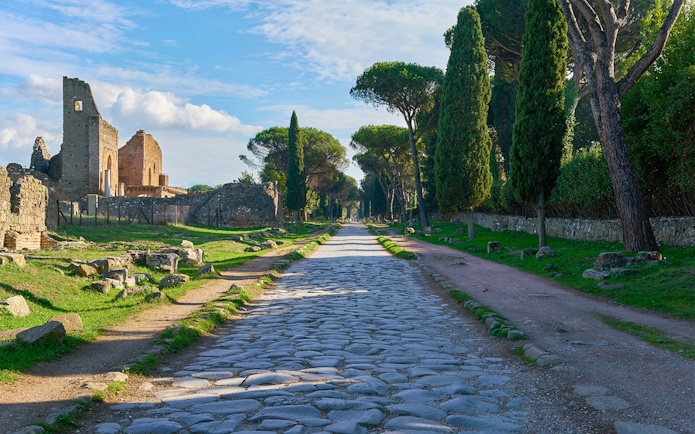 Ancient Roman road leading to the Catacombs of St. Callixtus, lined with cypress trees.