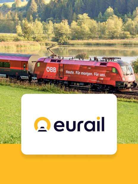 Eurail train traveling through scenic European countryside with lake and forest.
