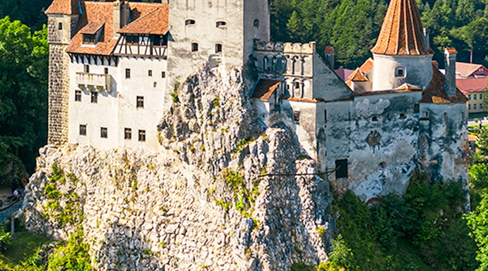 Bran Castle in Bucharest surrounded by lush green hills and forest.