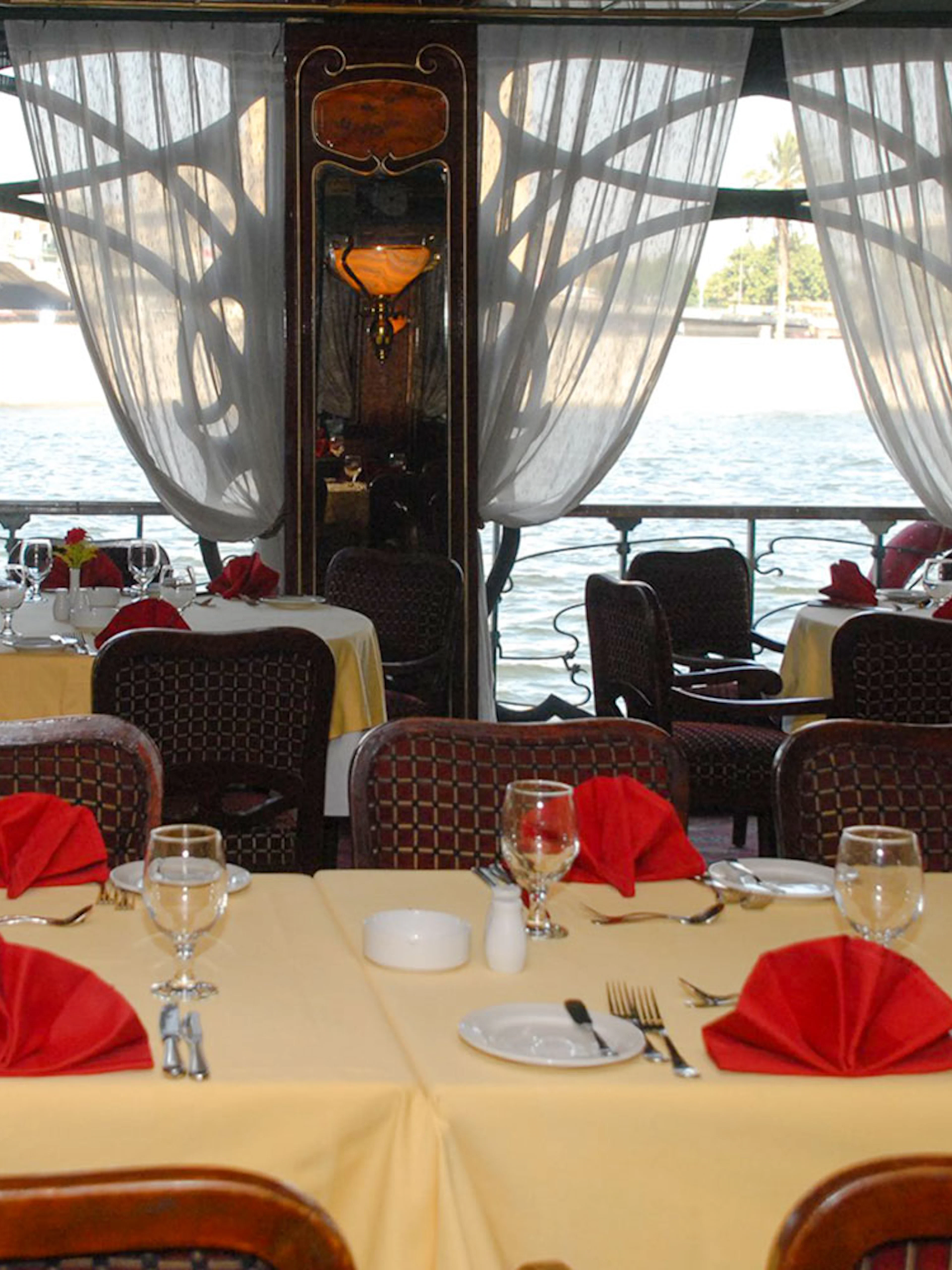 Dining tables set with red napkins on a Luxury Nile Dinner Cruise.