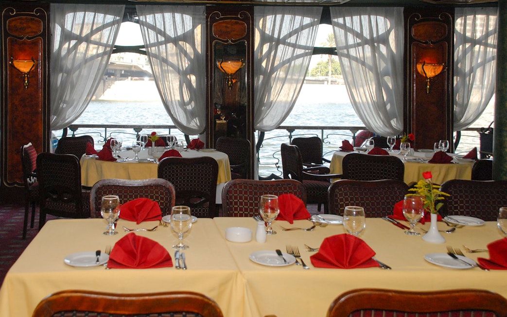 Dining tables set with red napkins on a Luxury Nile Dinner Cruise.