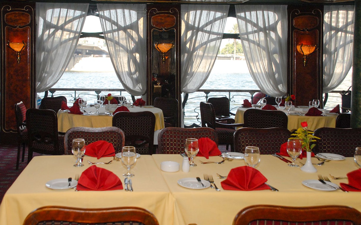Dining tables set with red napkins on a Luxury Nile Dinner Cruise.