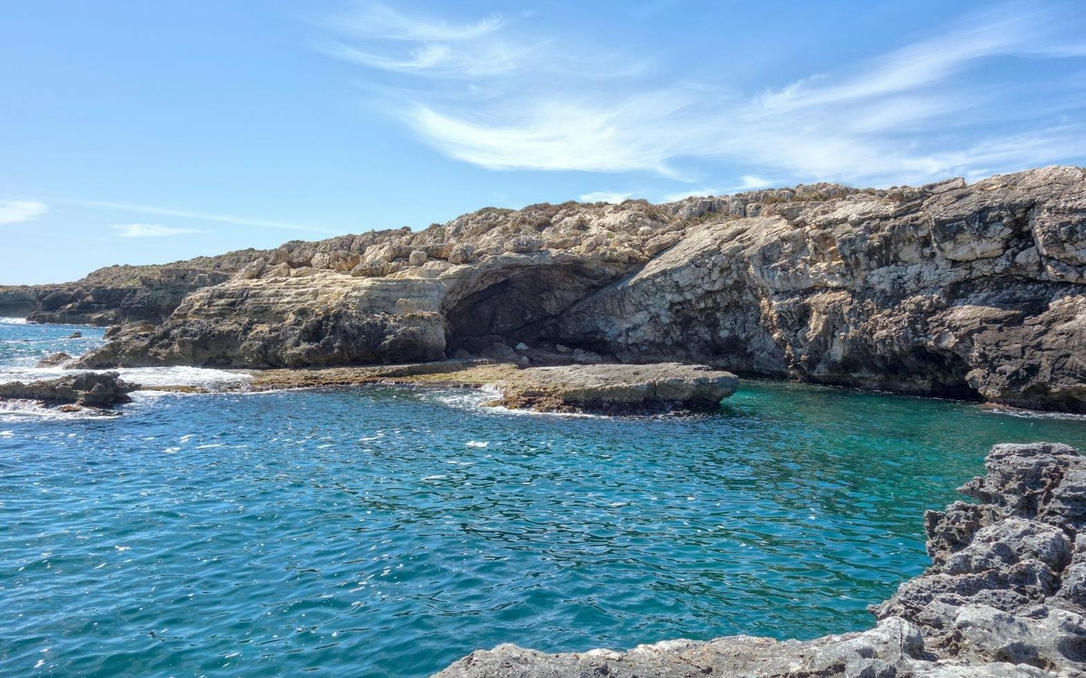 Ortiga Island grottos with rocky cliffs and blue water during boat tour.