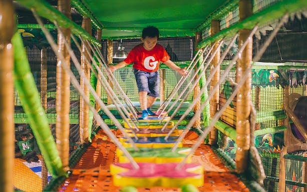 Child navigating rope bridge at Jungle Gym, KL East Mall, Malaysia.