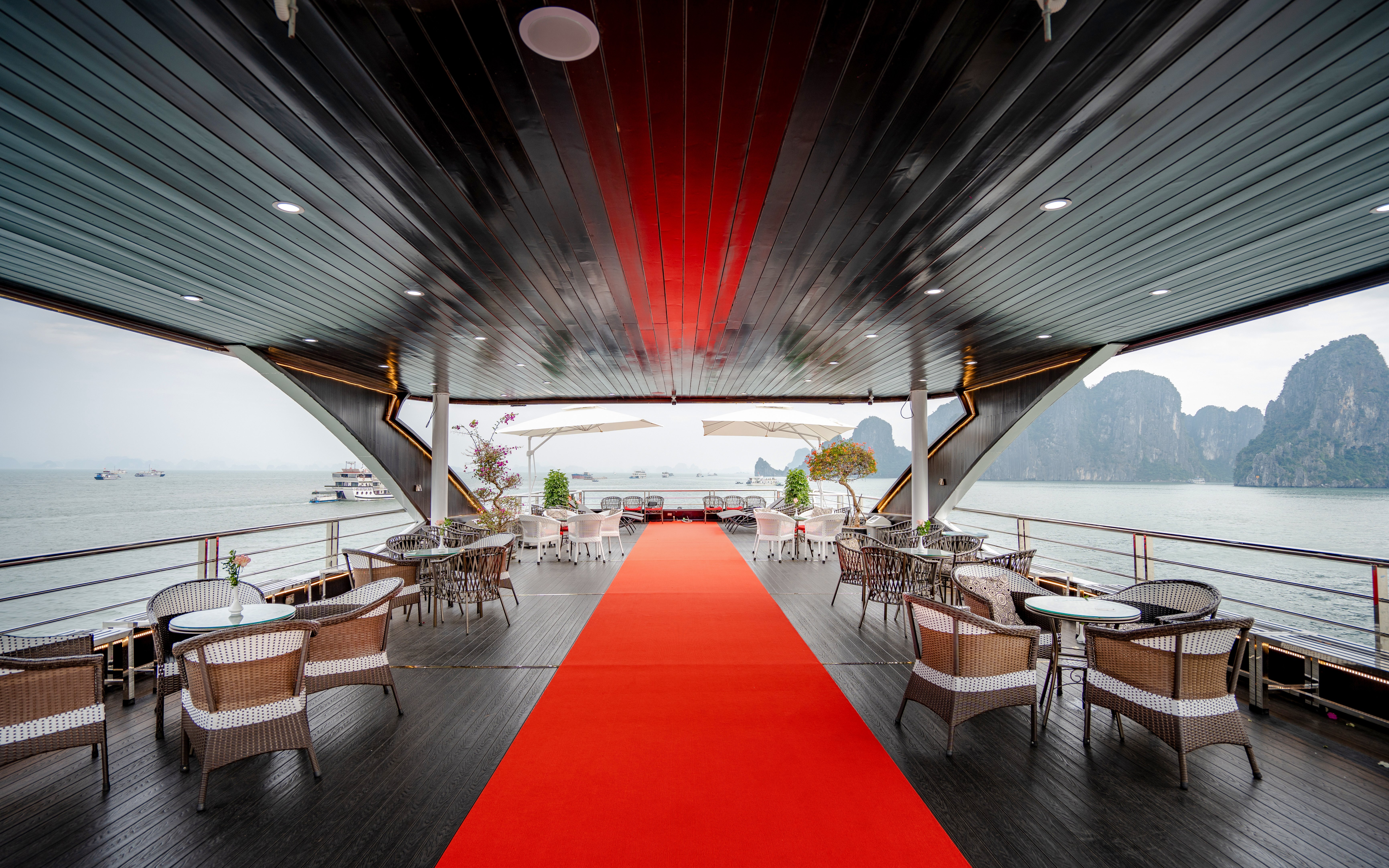Phong Hai Harmony Cruise deck with seating, red carpet, and view of Ha Long Bay.