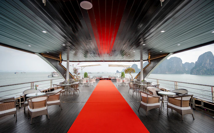 Phong Hai Harmony Cruise deck with seating, red carpet, and view of Ha Long Bay.