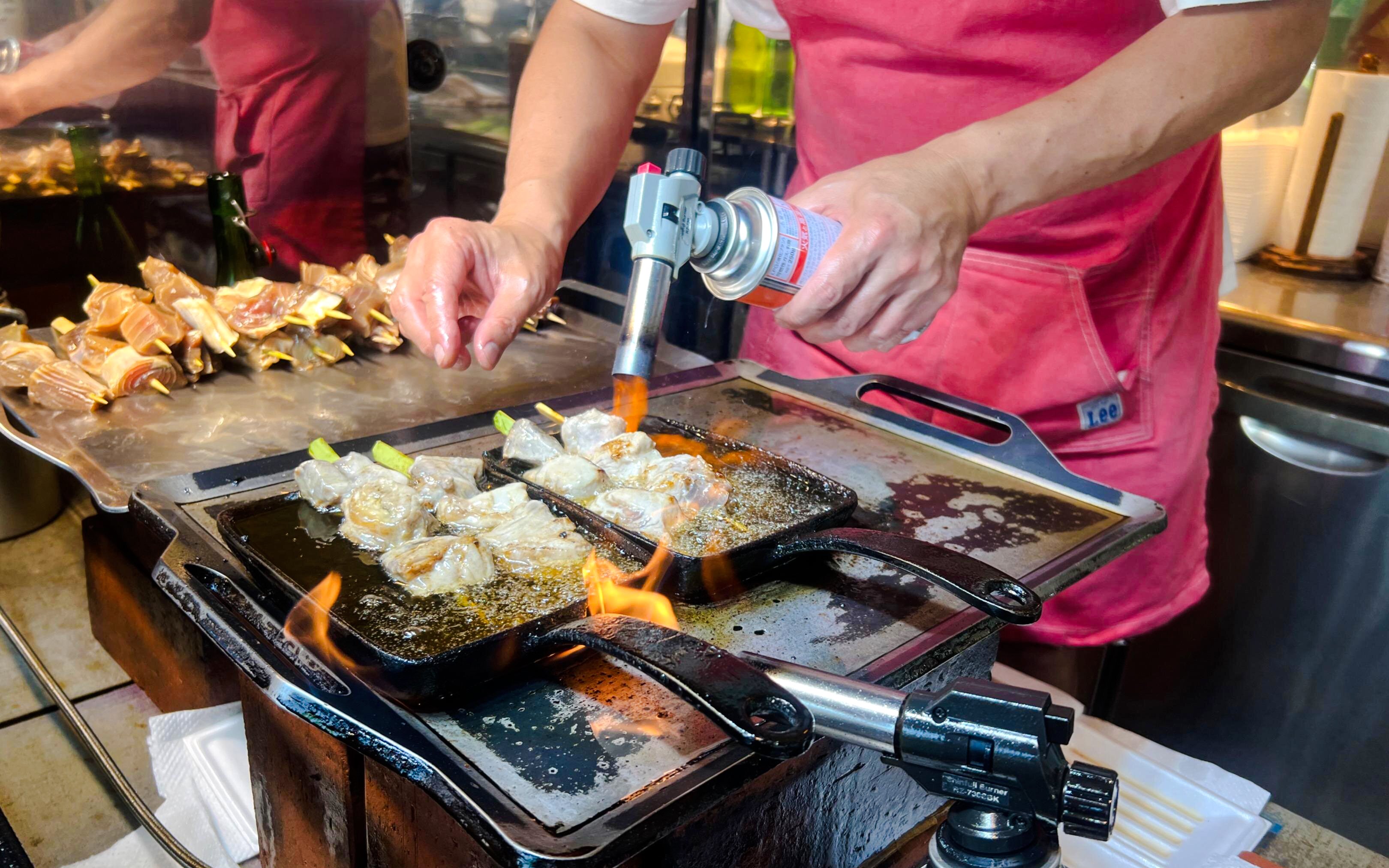 Yakitori being grilled with a torch at Tsukiji Fish Market, Tokyo food tour.