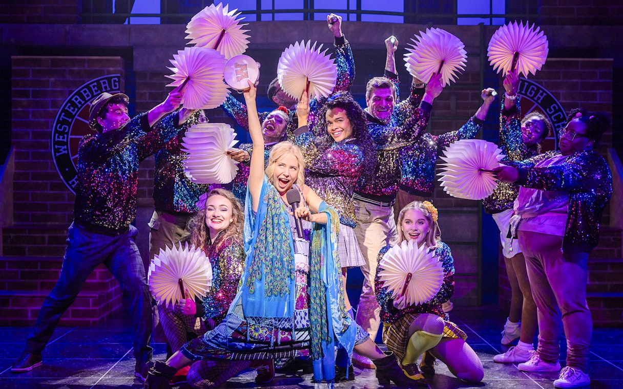 Performers on stage during "Heathers: The Musical" with colorful costumes and props.