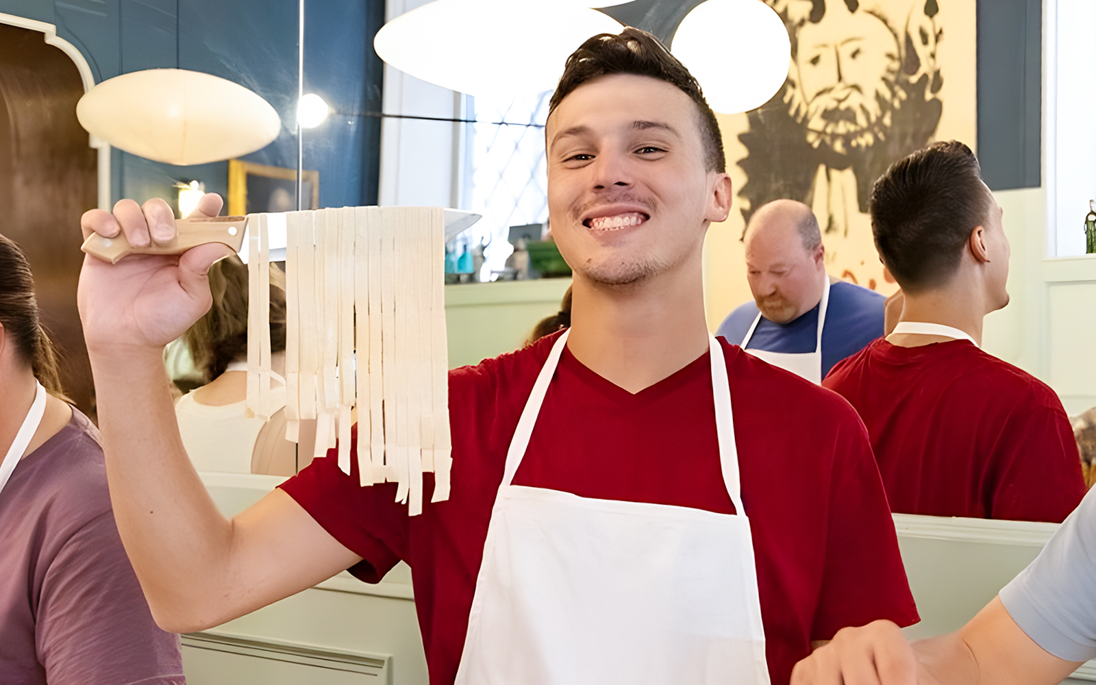 Cooking class participant holding fresh fettuccine in Rome near Piazza Navona.