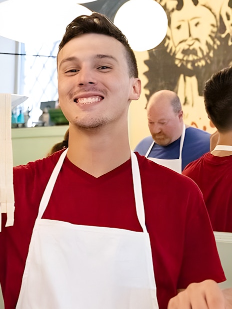 Cooking class participant holding fresh fettuccine in Rome near Piazza Navona.
