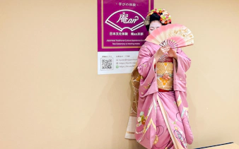 Maiko in pink kimono holding a traditional Japanese fan in Kyoto.