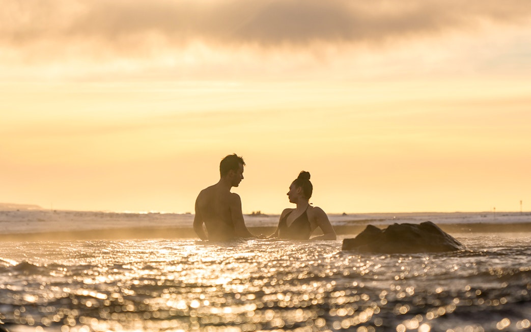 Couple relaxing in Sky Lagoon at sunset, Saman Pass tour.
