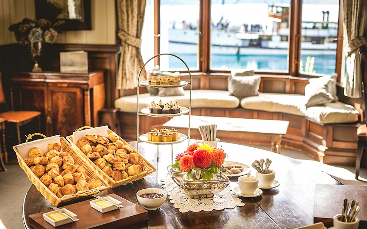Tea and scones setup at Walter Peak High Country Farm with lake view in background.