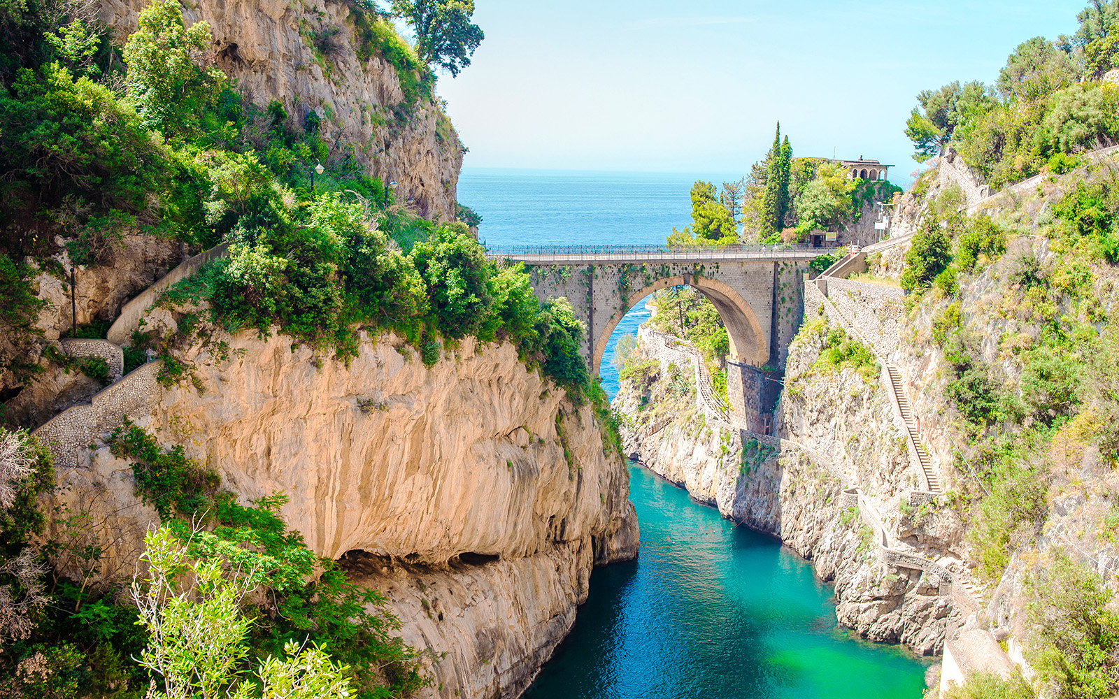 Bridge over Furore Fjord on Amalfi Coast, Italy, with turquoise water and rocky cliffs.