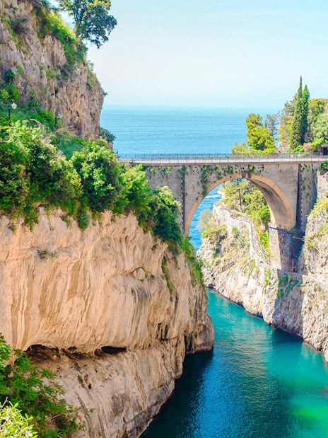 Bridge over Furore Fjord on Amalfi Coast, Italy, with turquoise water and rocky cliffs.