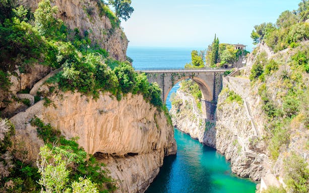 Bridge over Furore Fjord on Amalfi Coast, Italy, with turquoise water and rocky cliffs.