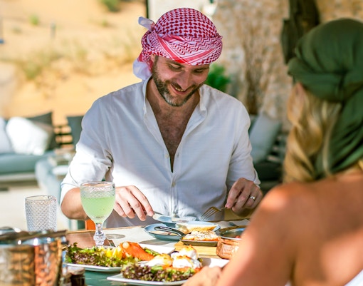 Two people enjoying a Michelin breakfast in the Dubai desert.