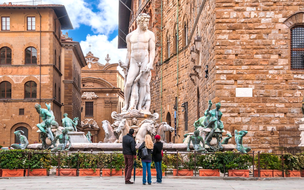 Fountain of Neptune in Piazza della Signoria, Florence, with tourists observing.