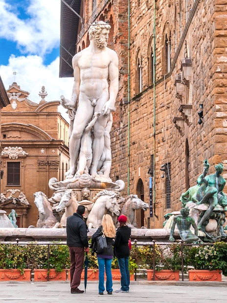 Fountain of Neptune in Piazza della Signoria, Florence, with tourists observing.