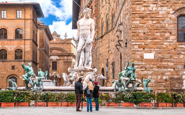 Fountain of Neptune in Piazza della Signoria, Florence, with tourists observing.