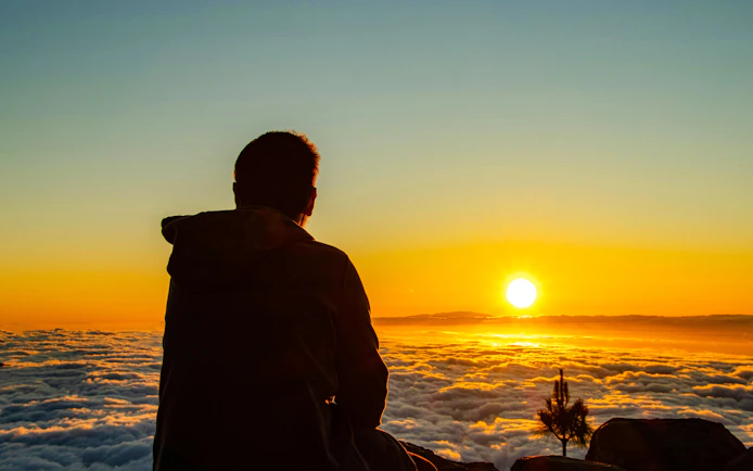 Man watching sunset over clouds at Teide National Park, Tenerife.
