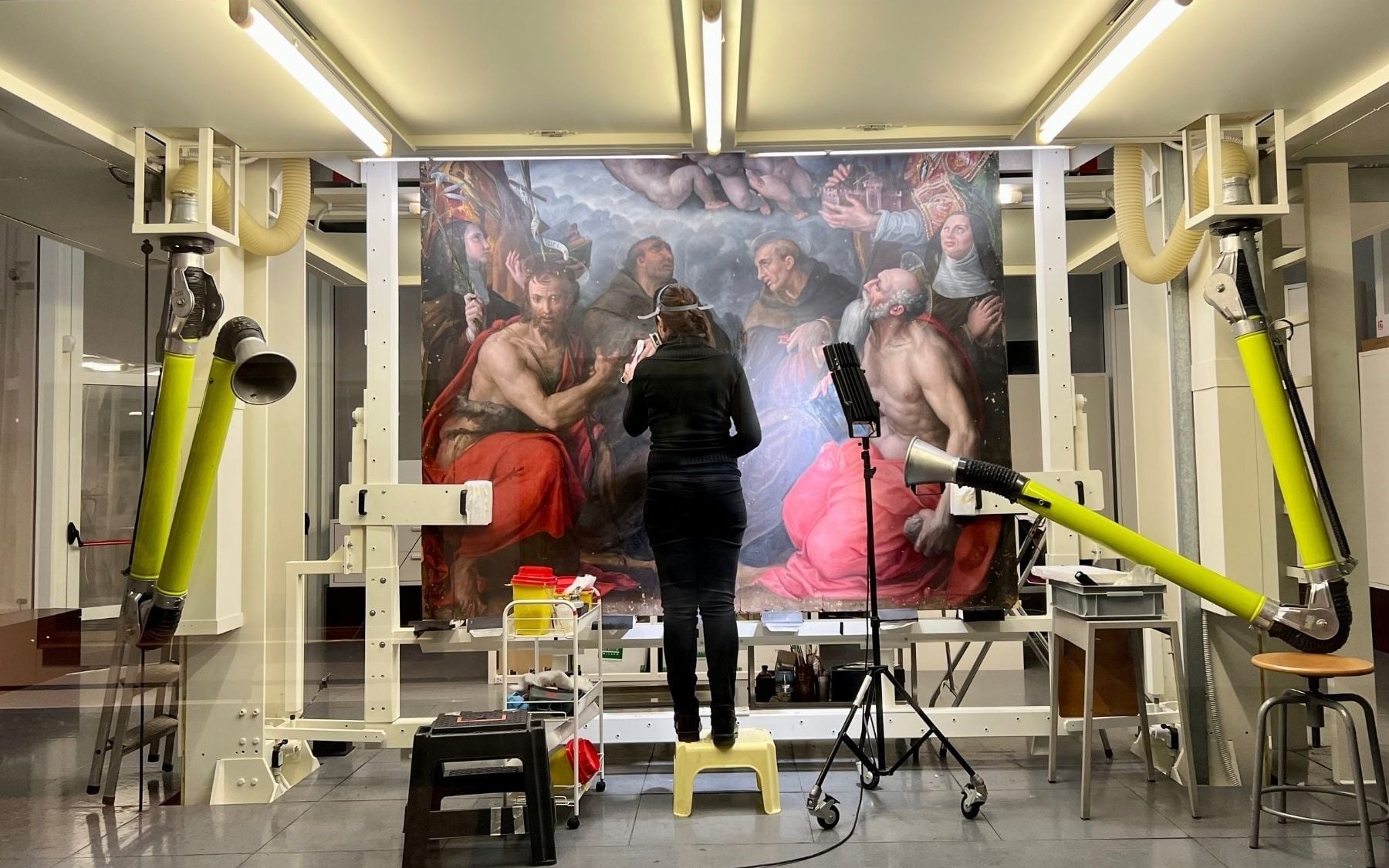Art restoration at Pinacoteca di Brera, Milan, with a conservator working on a large painting.