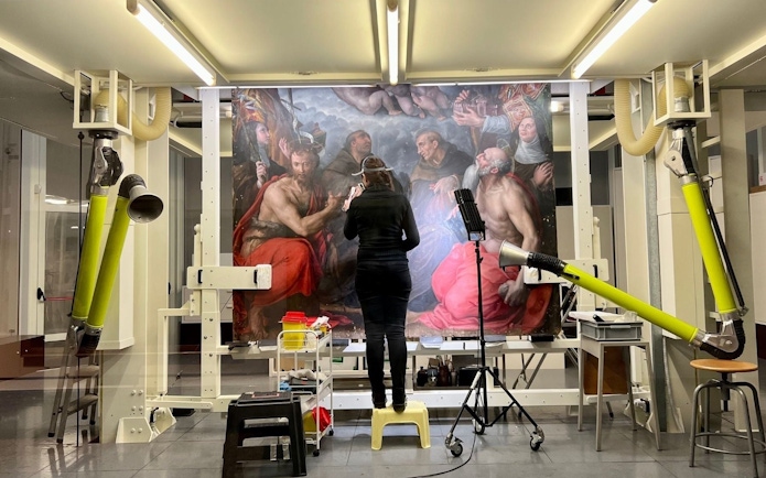 Art restoration at Pinacoteca di Brera, Milan, with a conservator working on a large painting.