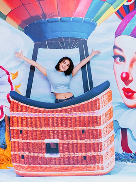Woman posing in front of colorful mural with hot air balloon, Singapore Cable Car Flexi Pass.