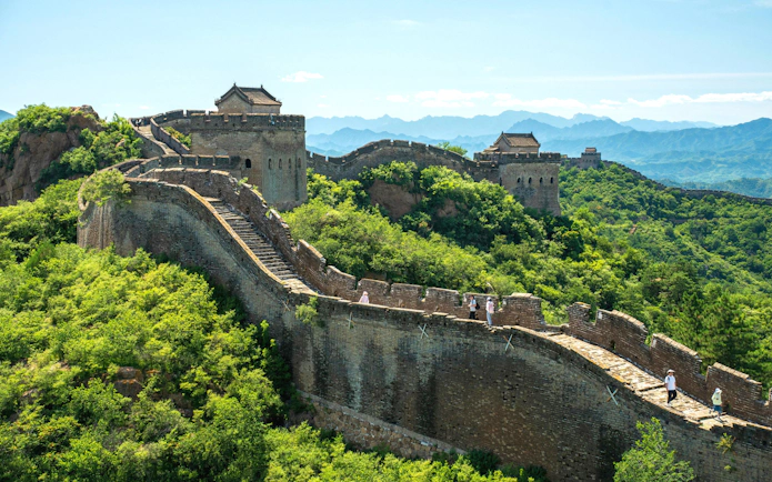 Great Wall of China winding through lush green hills, UNESCO World Heritage Site.