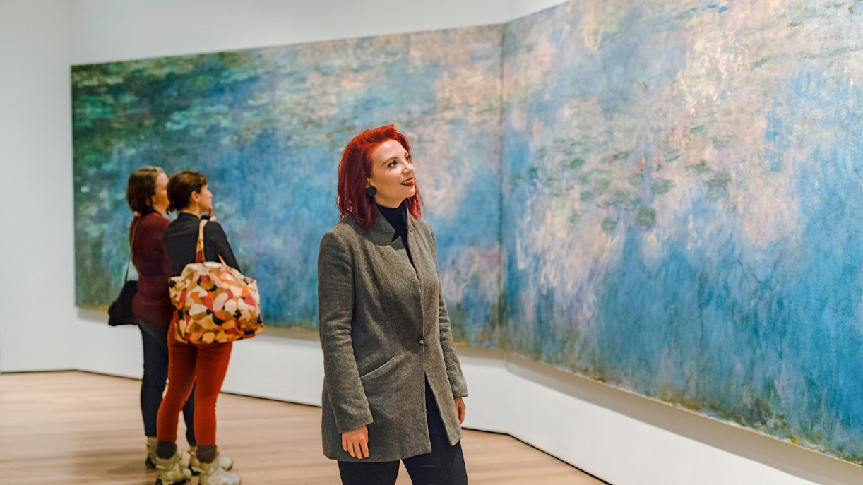 Woman viewing Monet's Water Lilies painting at a museum in MoMA