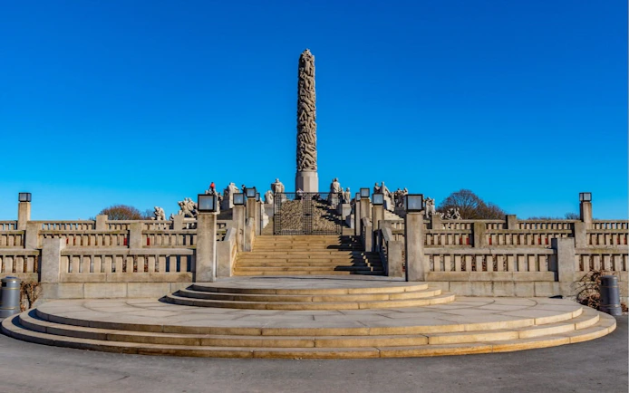 Vigeland Park's Monolith sculpture in Oslo under a clear blue sky.
