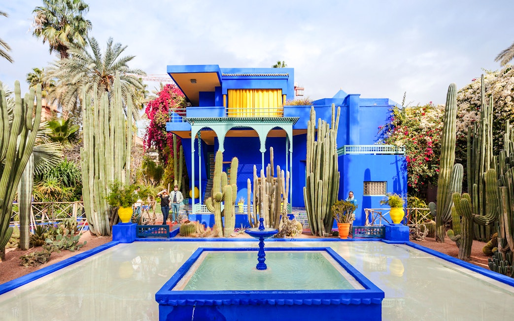 Jardin Majorelle's vibrant blue villa surrounded by cacti and palm trees in Marrakech.