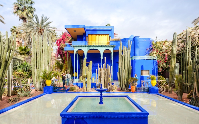 Jardin Majorelle's vibrant blue villa surrounded by cacti and palm trees in Marrakech.
