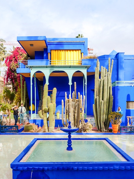 Jardin Majorelle's vibrant blue villa surrounded by cacti and palm trees in Marrakech.