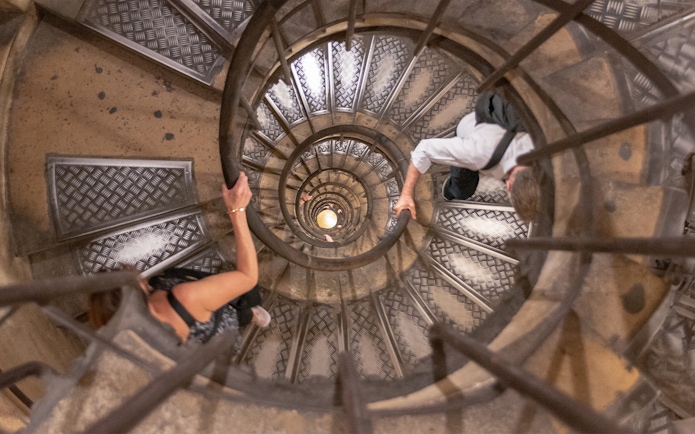 Visitors ascending spiral staircase to Arc de Triomphe rooftop, Paris.