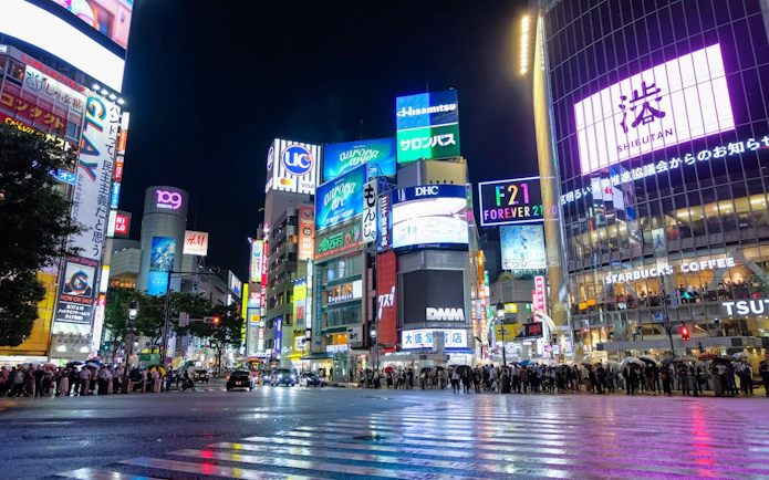 Shibuya Crossing at night with illuminated billboards and crowds, Tokyo.